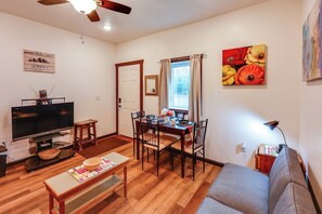 A living room with a television, dining table, chairs, a sofa, and a ceiling fan. - Cozy Apartment Near UAF & Downtown Fairbanks! (Fairbanks)