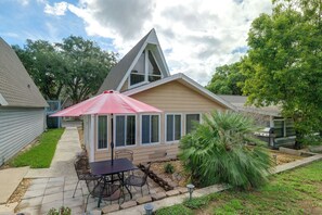 A residential property with a patio, a table and chairs, a red umbrella, and a garden with a palm tree. - Lake Breeze Bungalow: 3 Mi to State Park! (Clermont)