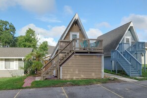 Ein zweistöckiges Haus mit einer Holzterrasse und einer blauen Treppe.