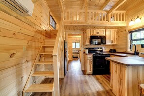 Un intérieur en bois comprenant une cuisine, un escalier et une vue par une fenêtre.