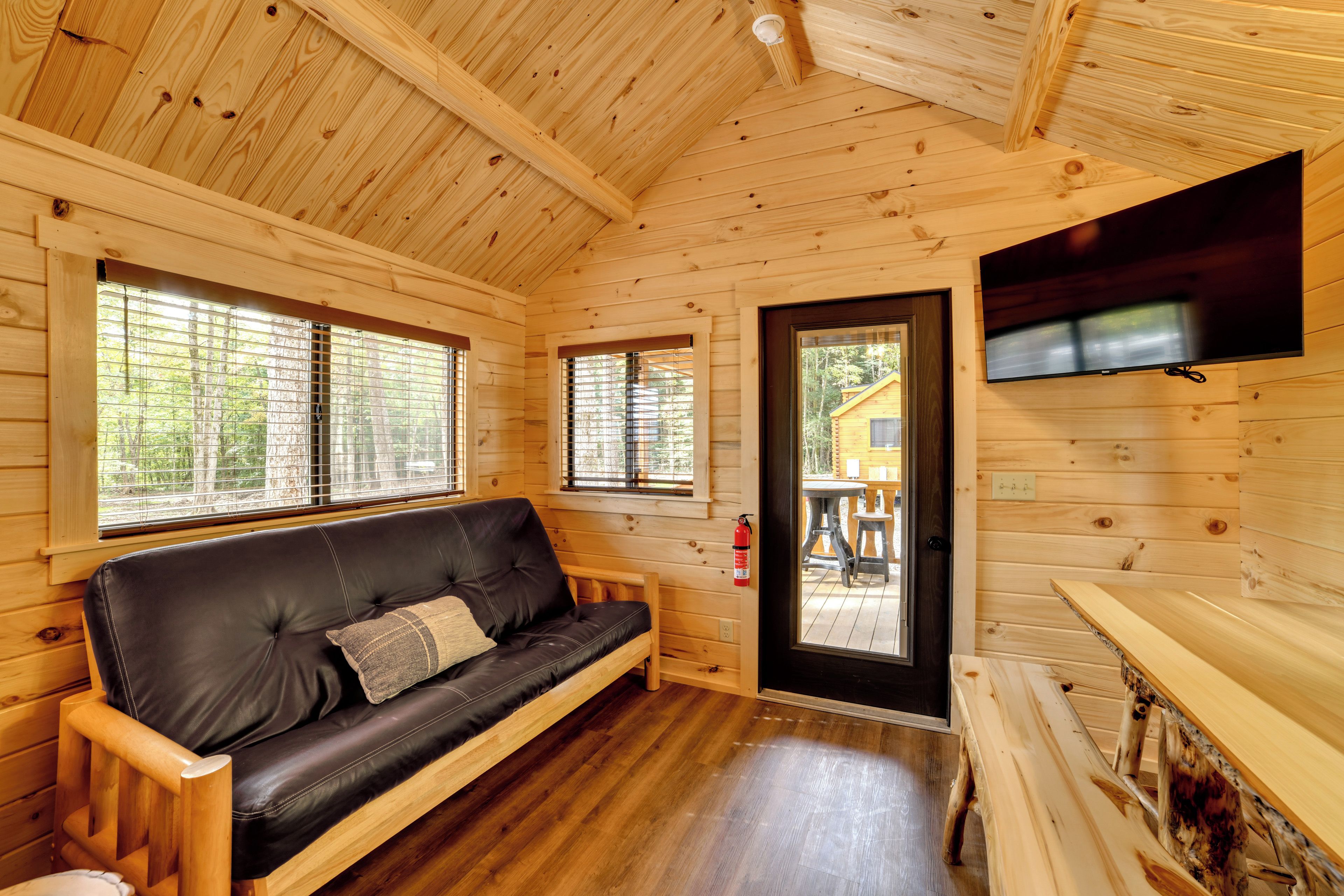 L’intérieur d’un chalet en bois, avec un canapé en cuir, des murs en bois et un téléviseur fixé au mur.