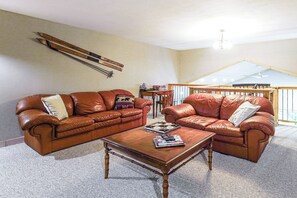 Un salon avec deux canapés en cuir, une table basse et un plancher en bois.