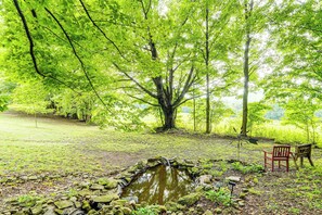 Un paysage naturel avec un étang, des rochers et une chaise en bois.