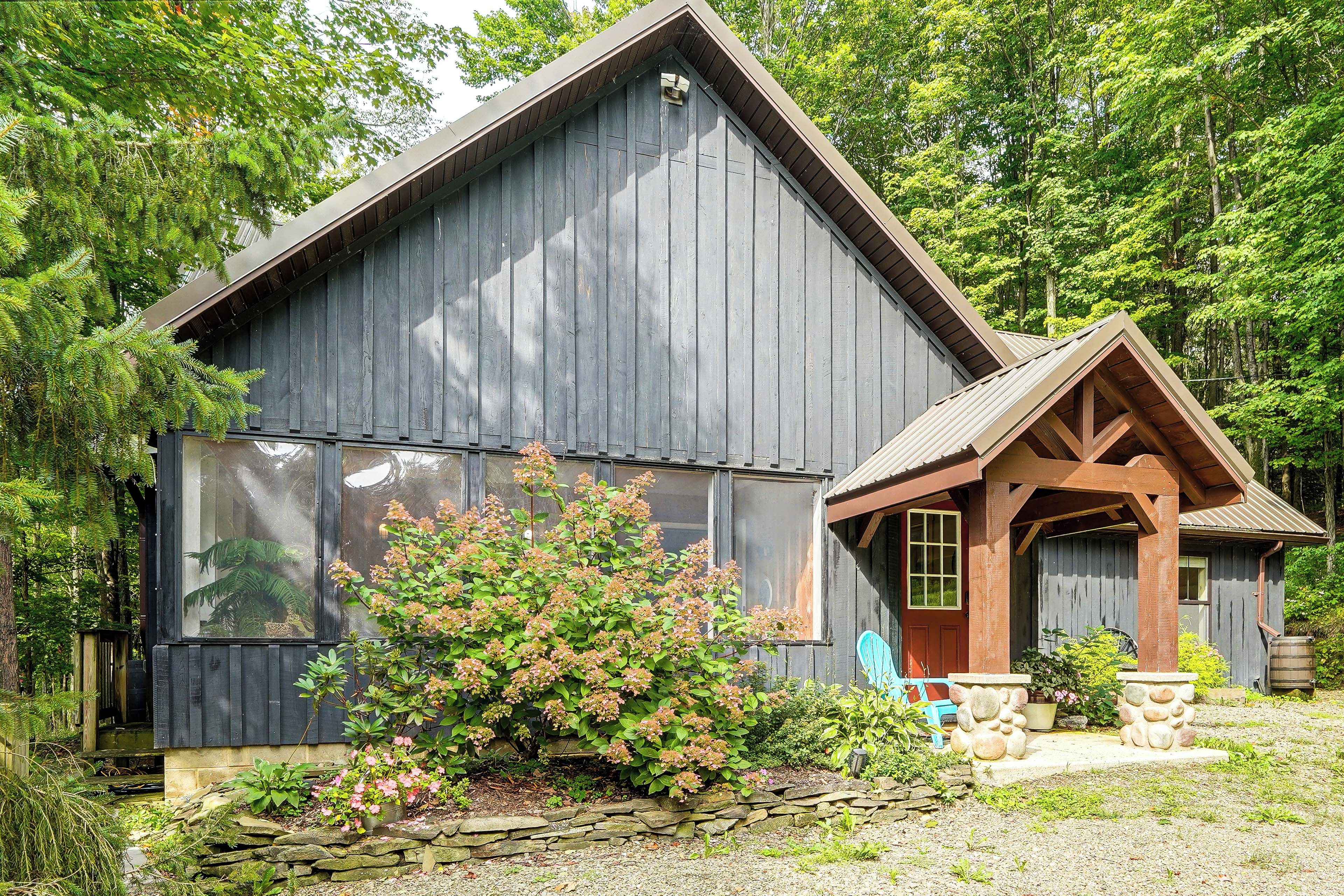 A rustic cabin with a large window, a stone foundation, and a wooden porch.