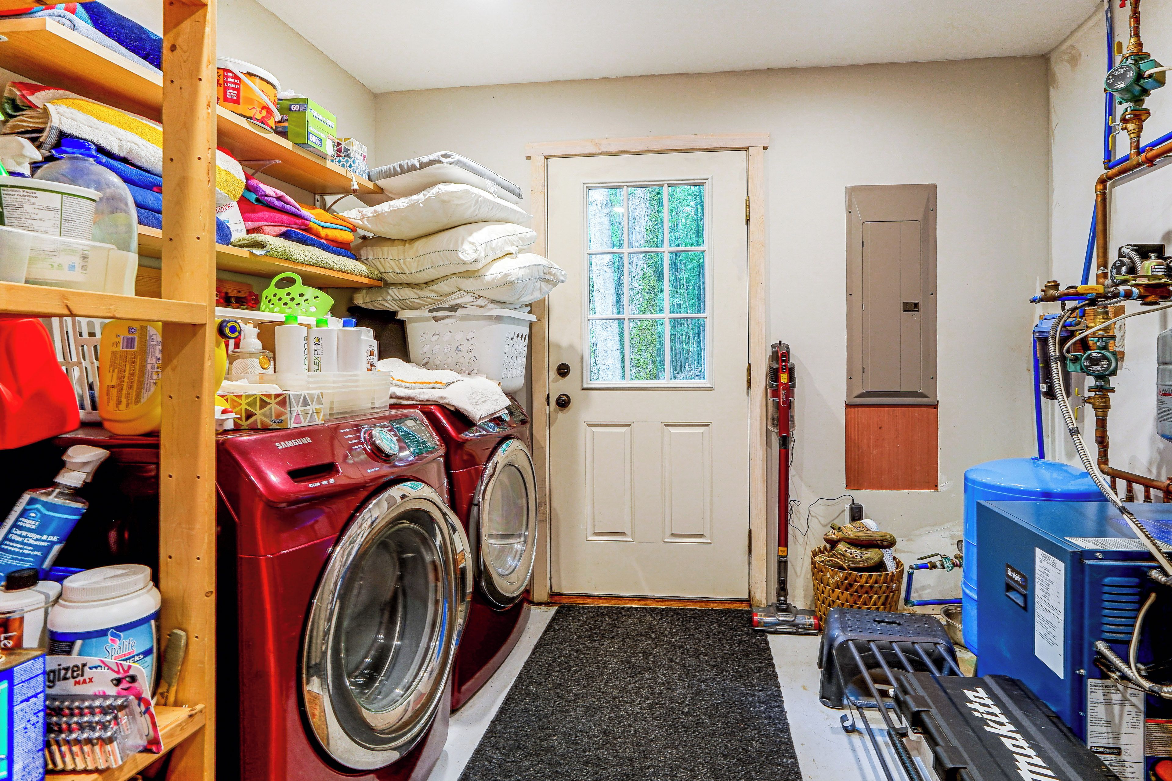 A laundry room with a washing machine, dryer, and various cleaning supplies.