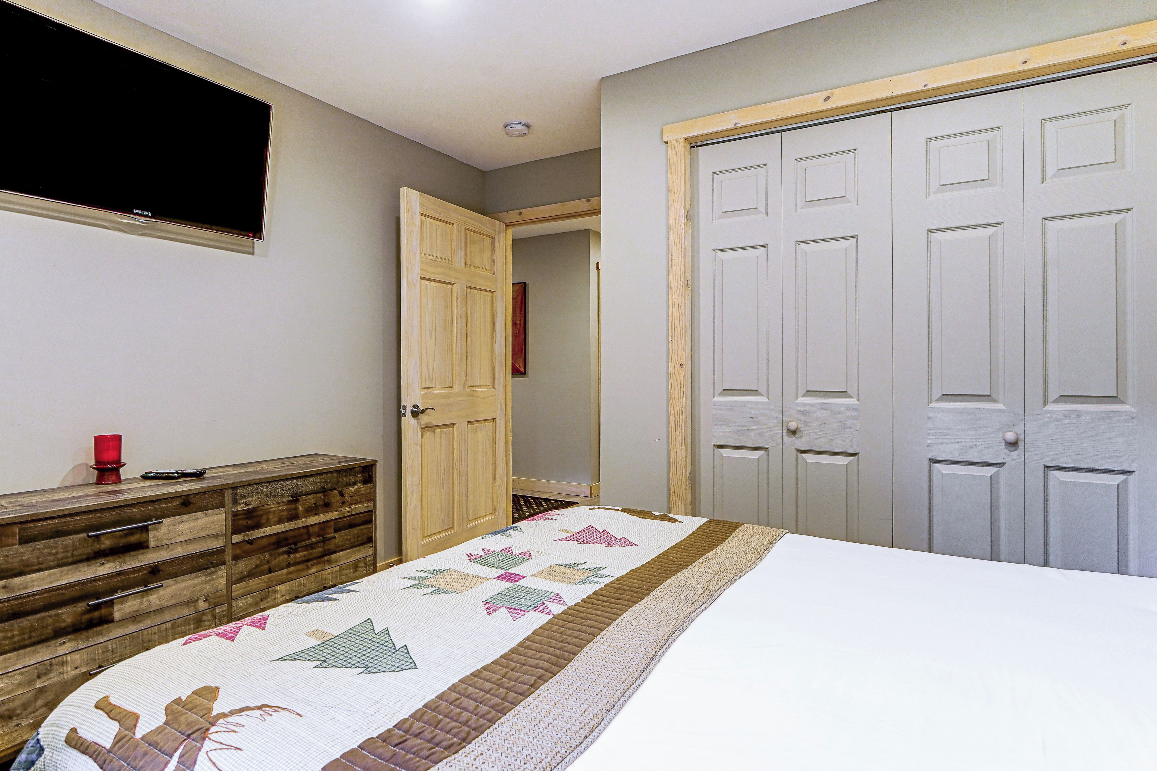 Une chambre à coucher avec un lit, une commode, un placard et un téléviseur fixé au mur.