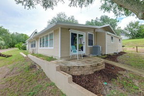 A single-story house with a covered porch, a small outdoor seating area, and a well-maintained lawn. - 'Tropical Hideaway' 3 Mi to Lake Louisa State Park (Clermont)