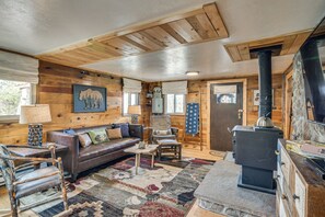 A cozy cabin interior with a wooden interior, a fireplace, a sofa, and a dining table. - Historic Wondervu Cabin Near Gross Reservoir (Golden)