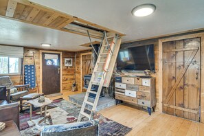 Een landelijk houten interieur met een houten trap, een televisie en een stenen open haard.