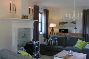 Ein Wohnzimmer mit Kamin, einer Couch, einem Couchtisch und einer Deckenleuchte.