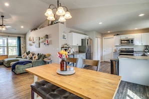 A spacious kitchen with modern appliances, a dining area with a wooden table and bench, and a living room with a sofa and decorative pillows. - Scenic St Claire Home: Deck + Spacious Yard (St Clair)