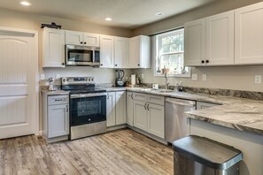 A modern kitchen with white cabinetry, stainless steel appliances, and a marble countertop. - Scenic St Claire Home: Deck + Spacious Yard (St Clair)