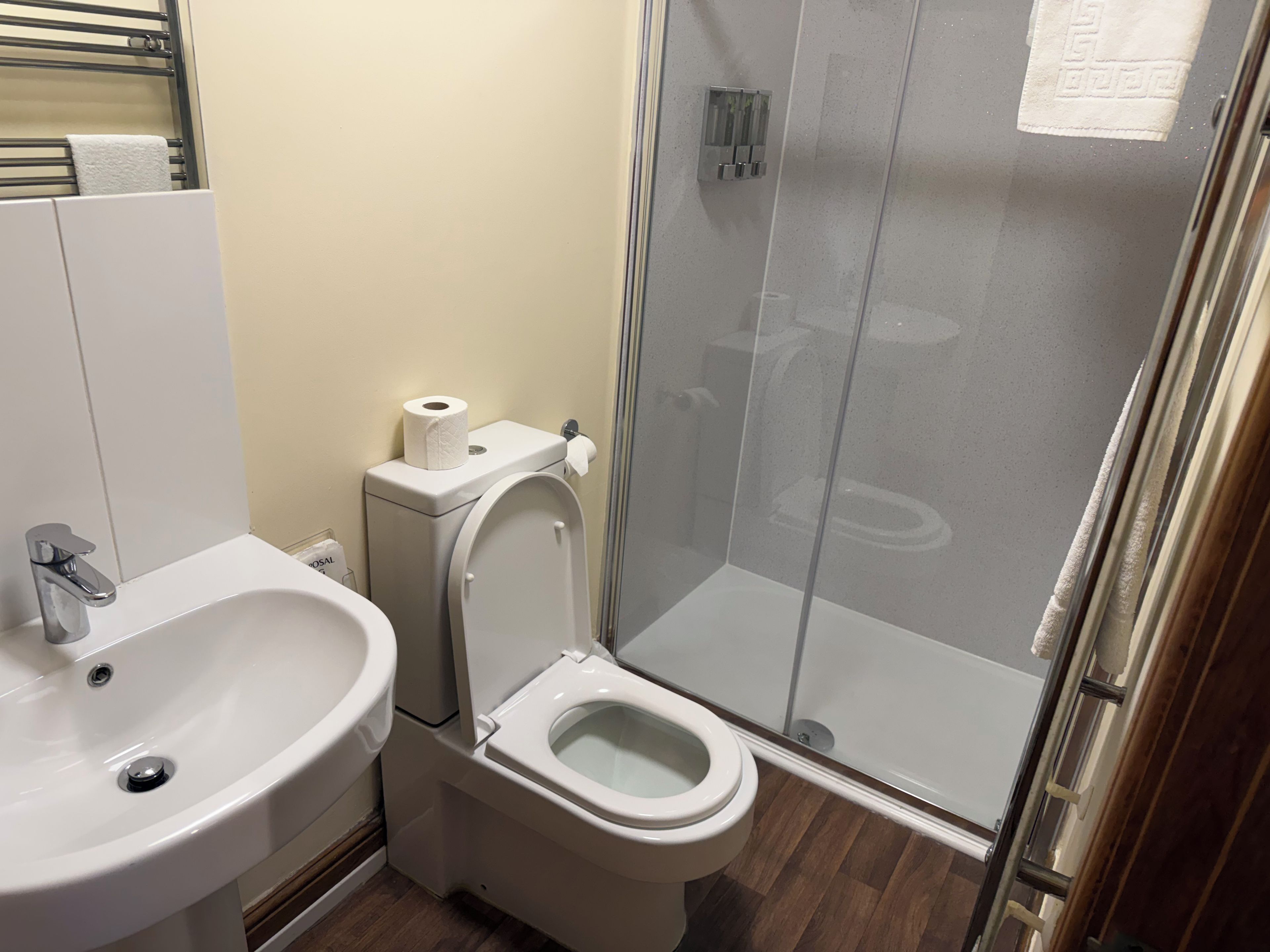 Ein Badezimmer mit Toilette, Waschbecken und einer Duschkabine aus Glas.
