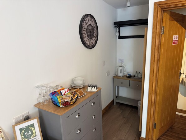 A hotel room with a kitchenette, a clock on the wall, and a 'No smoking' sign.