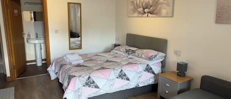 A bedroom with a bed, bedside table, and a grey sofa.