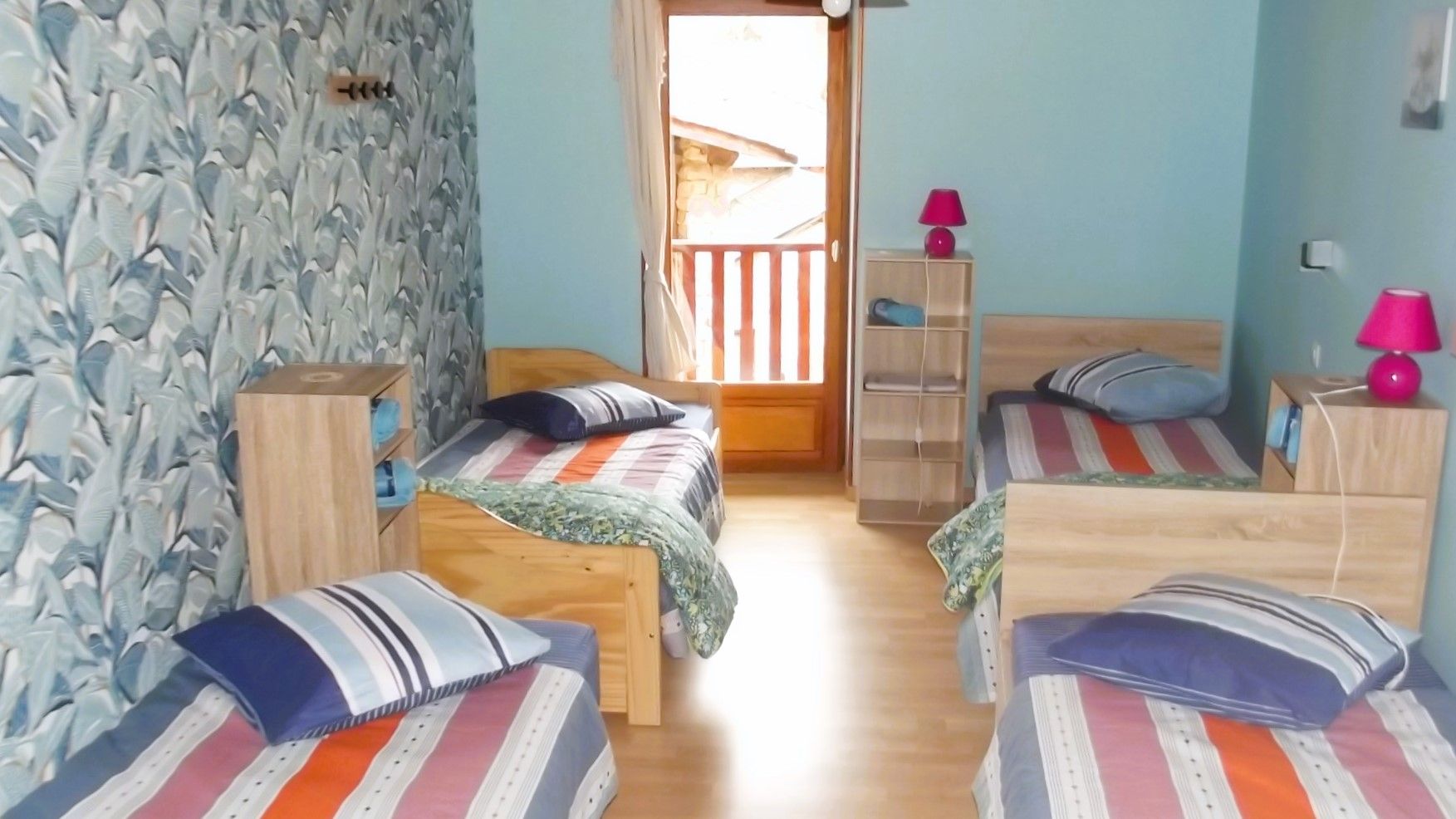 Ein Zimmer mit zwei hölzernen Betten, einer Steinwand, einer Holztür und einem kleinen Holzschrank.