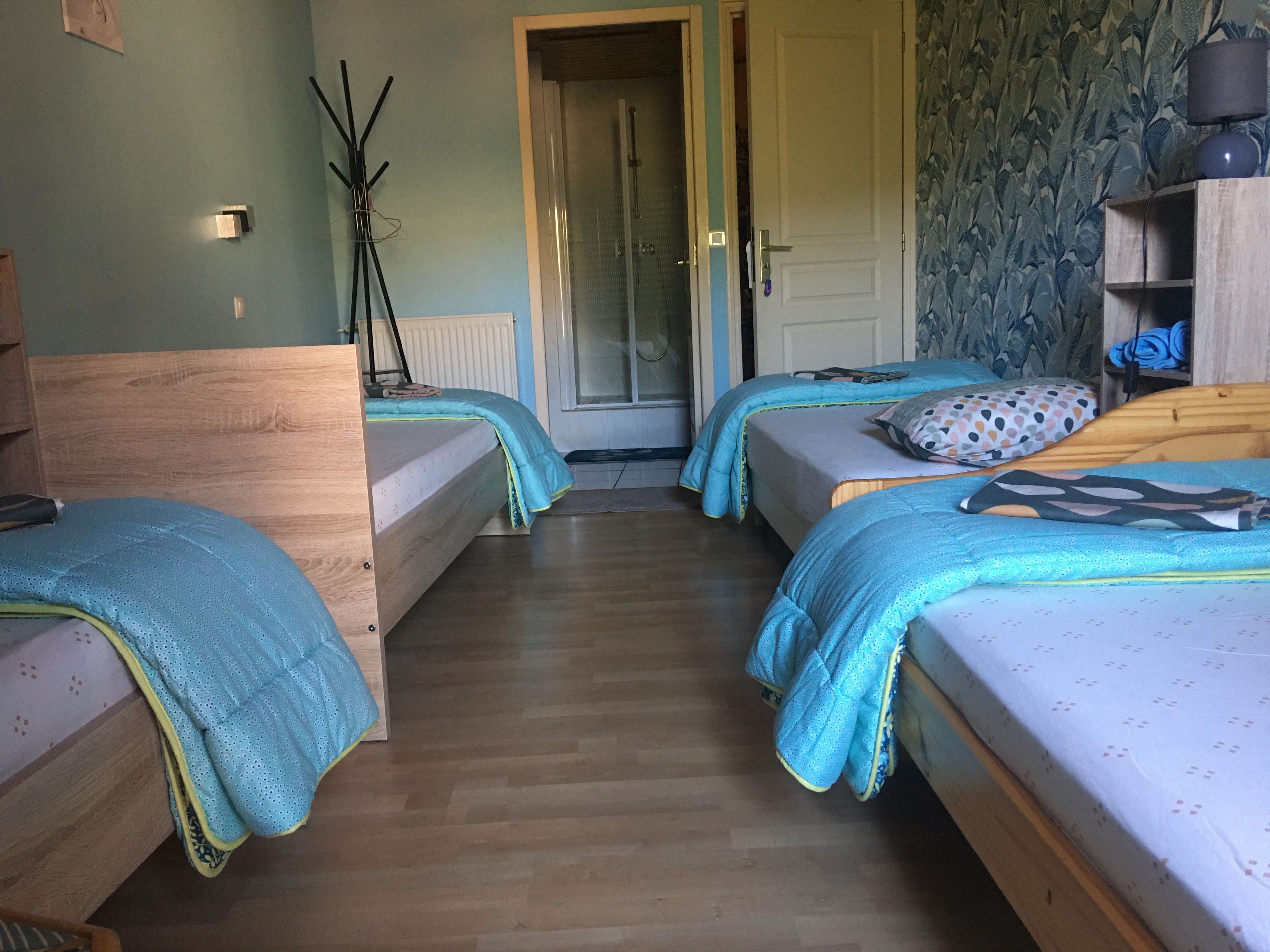 A room with two single beds, a wooden wardrobe, a radiator, and a door leading to another room.