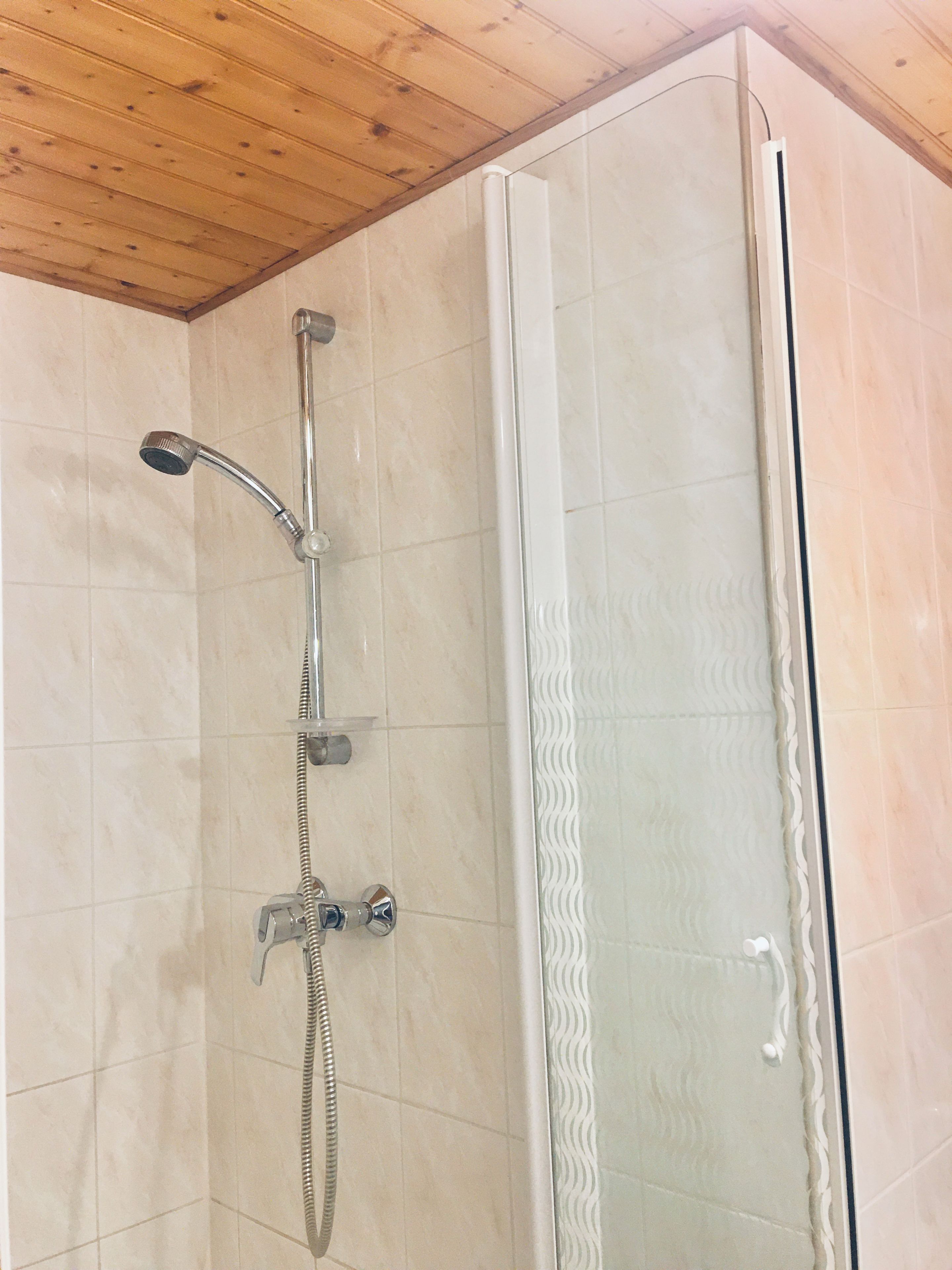 Ducha con cabezal de ducha manual y cabezal de ducha fijo, ambos instalados en una pared con revestimiento de azulejos.