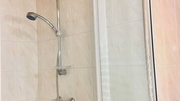 Ducha con cabezal de ducha manual y cabezal de ducha fijo, ambos instalados en una pared con revestimiento de azulejos.