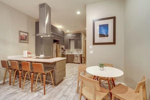 A modern kitchen with a central island, stainless steel appliances, and a dining area with wooden chairs and a white table. - Near Trails, Skiing & NAU! Family-Ready Home (Flagstaff)