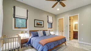 A bedroom with a bed, nightstands, a crib, a ceiling fan, and a framed picture on the wall. - Near Trails, Skiing & NAU! Family-Ready Home (Flagstaff)