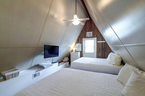 A bedroom with a bed, a television, a ceiling fan, and a door with a sign. - 'Good Vibes Cottage' Pool & Pier on Lake Louisa (Clermont)