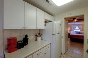 A compact kitchen with white cabinets, a built-in refrigerator, a toaster, and a knife holder on the countertop. - 'Good Vibes Cottage' Pool & Pier on Lake Louisa (Clermont)