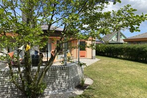 Una propietat residencial amb mur de maó, un arbre i un jardí ben cuidat.