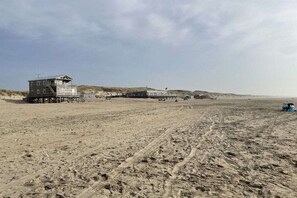 A beach with a lifeguard tower and a building with a balcony. - Bungalow with 1 bedroom (Den Helder, Julianadorp)
