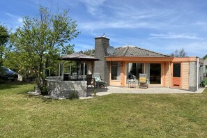 A house with a patio, a chimney, and a satellite dish. - Bungalow with 1 bedroom (Den Helder, Julianadorp)