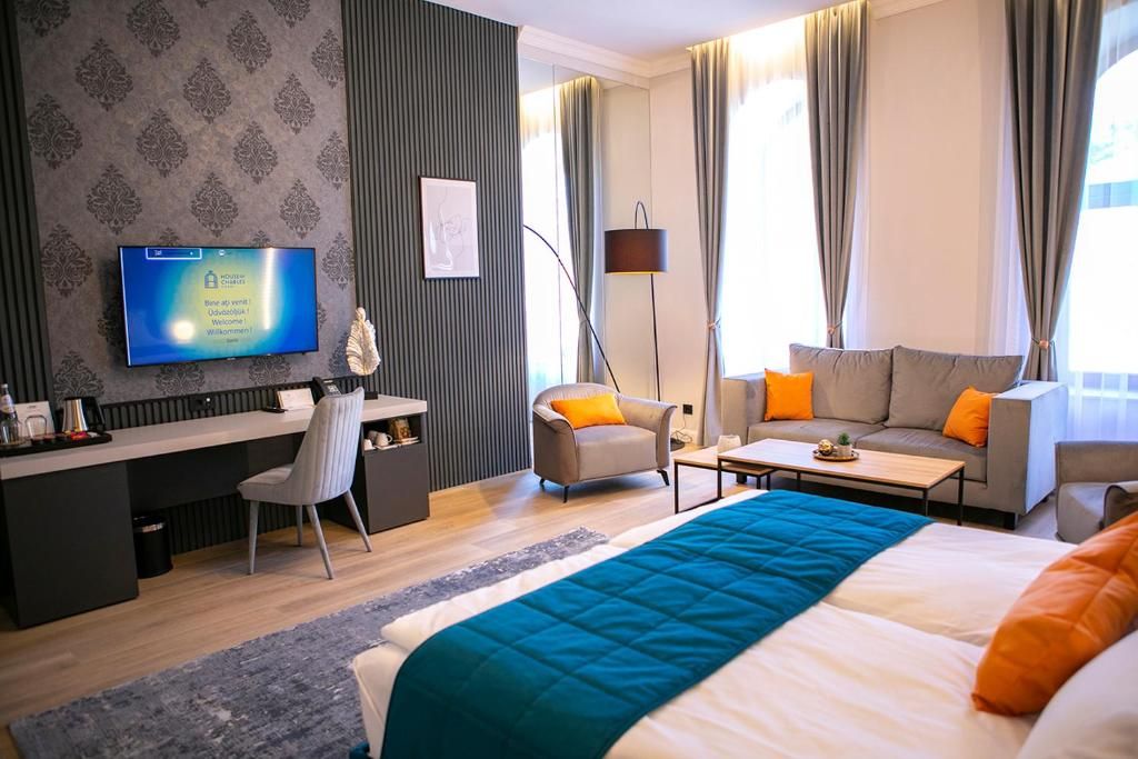 Una habitación de hotel con una cama, dos sofás, un escritorio, un televisor y una lámpara.