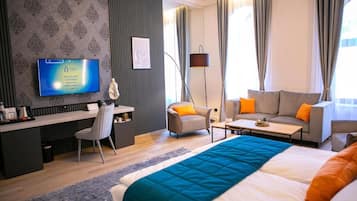 Una habitación de hotel con una cama, dos sofás, un escritorio, un televisor y una lámpara.