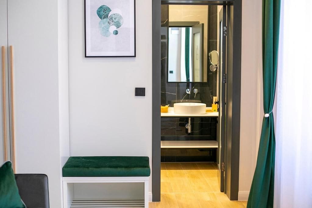 A modern bathroom with a sink, mirror, and green curtains.