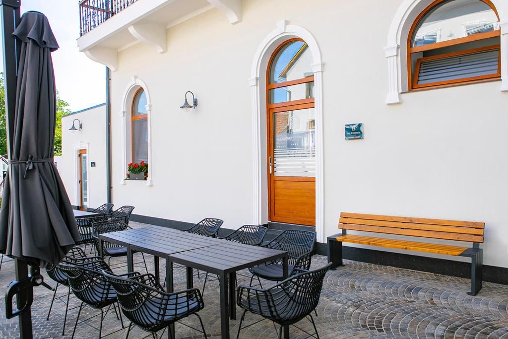 Un área de estar al aire libre con una mesa, sillas, un banco y una sombrilla.