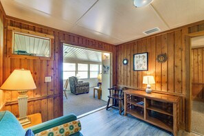 Ein Holzinterieur mit einer Couch, zwei Lampen, einem Esstisch und einem Spiegel an der Wand.