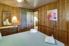 Une chambre d’hôtel avec des boiseries, un lit doté d’un matelas matelassé, une commode avec une lampe, un miroir et un tableau accroché au mur.