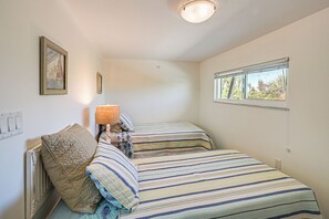A bedroom with a single bed, a nightstand, a lamp, a framed picture, a window, and a wall socket. - Secluded Island Escape on Little Gasparilla Island (Placida)