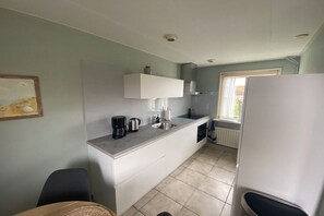 Eine kompakte Küche mit integriertem Spülbecken, einer Kaffeemaschine und einem Fenster, das für natürliches Licht sorgt.