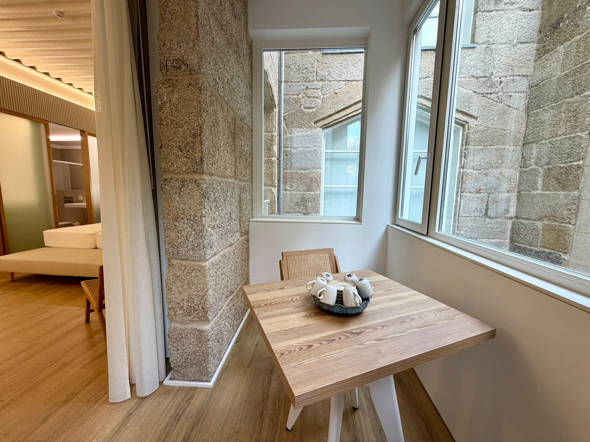 A corner room with a wooden table, a stone wall, and a window.
