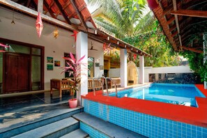 A pool area with a tiled edge, a wooden deck, and a potted plant. - Lux Beachfront 2 BHK Private Pool Villa in Morjim | 100mtr to Beach (Morjim)