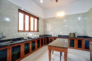 A kitchen with a marble countertop, wooden cabinets, a window with blinds, and a microwave on the counter. - Lux Beachfront 2 BHK Private Pool Villa in Morjim | 100mtr to Beach (Morjim)