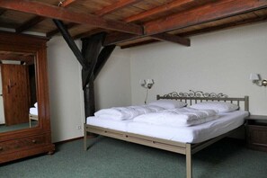 Een slaapkamer met een houten bedframe, nachtkastje, spiegel en een kledingkast.