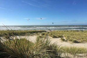 Een strand met duinen en een heldere lucht.