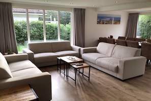 Ein großzügiges Wohnzimmer mit einer Sofagarnitur, einem Couchtisch und einem Essbereich mit Stühlen.