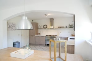 A modern kitchen with a central island, a hanging light fixture, and a wall with decorative text. - Holiday home with 3 bedrooms (Callantsoog)