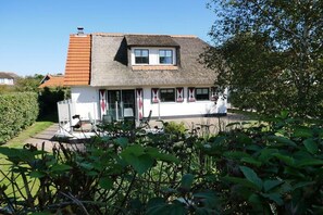 Ein Haus mit einem Strohdach, einer kleinen Veranda und einem Vorgarten.