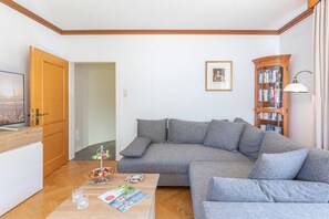 A living room with a grey sofa, a coffee table with a magazine, and a bookshelf. - Holiday home with 3 bedrooms (Langenhorn)