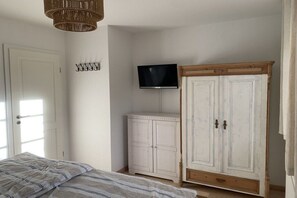 Een slaapkamer met een bed, een kledingkast, een televisie en een deur.