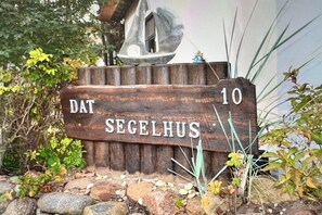 Une plaque en bois portant l’inscription « DAT SECELHUS 10 », indiquant un lieu ou le nom d’une propriété.