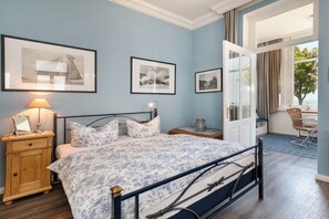 Ein Schlafzimmer mit einem Bett, Nachttischen, einer Lampe und gerahmten Bildern an der Wand.